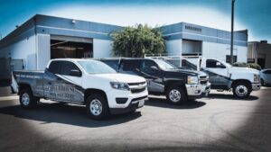 Three branded trucks parked outside a building.
