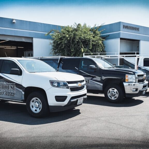 Three branded trucks parked outside a building.
