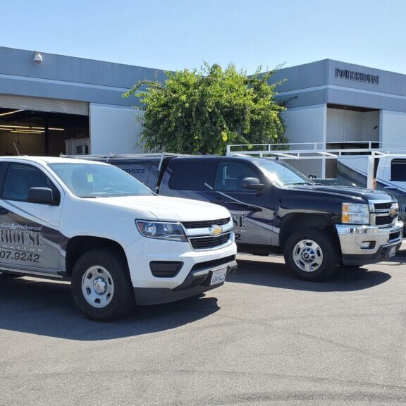 Three trucks parked outside industrial building.